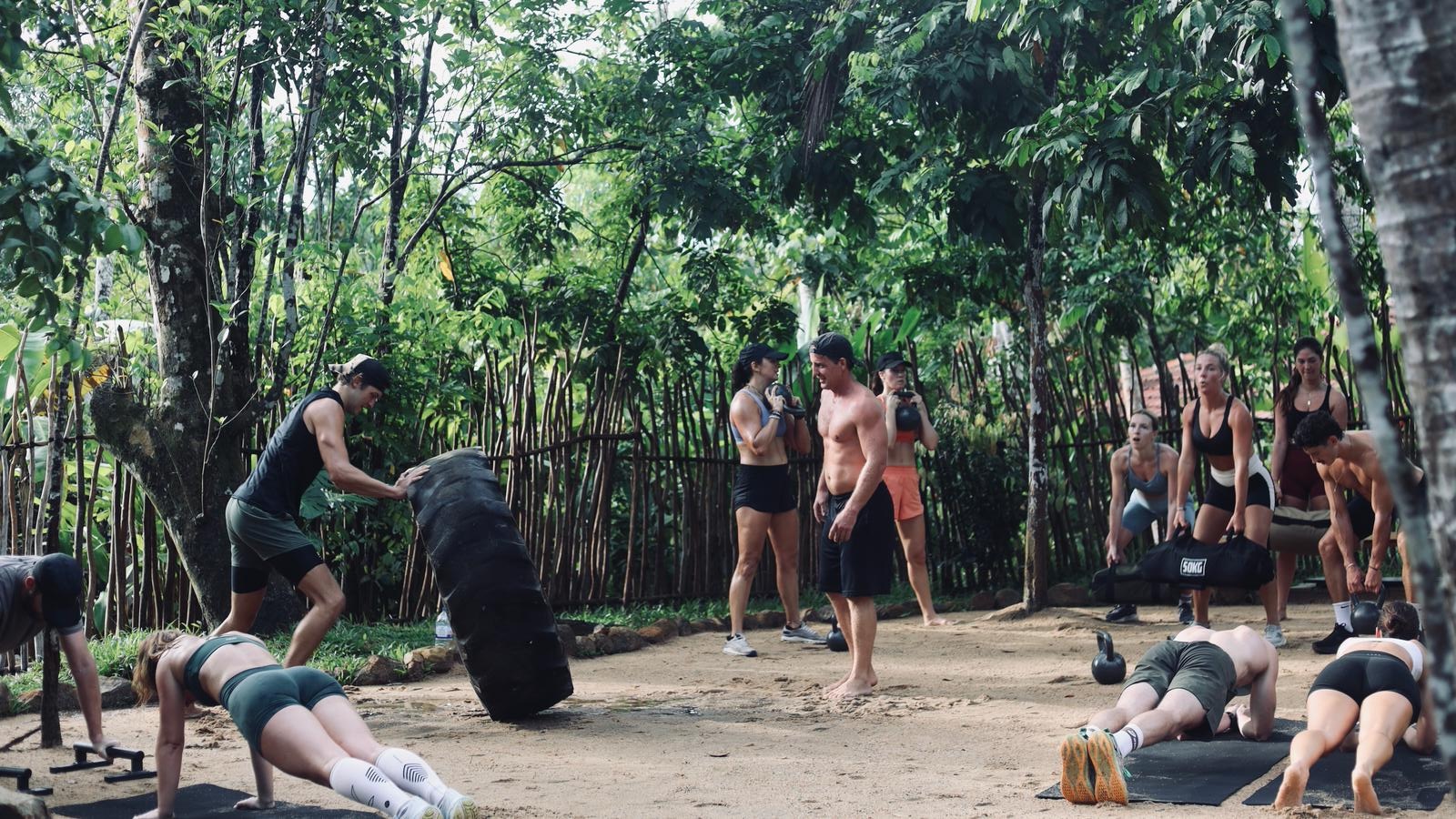 Group session in the outdoor gym — a tyre being flipped, kettlebells and push-ups all around